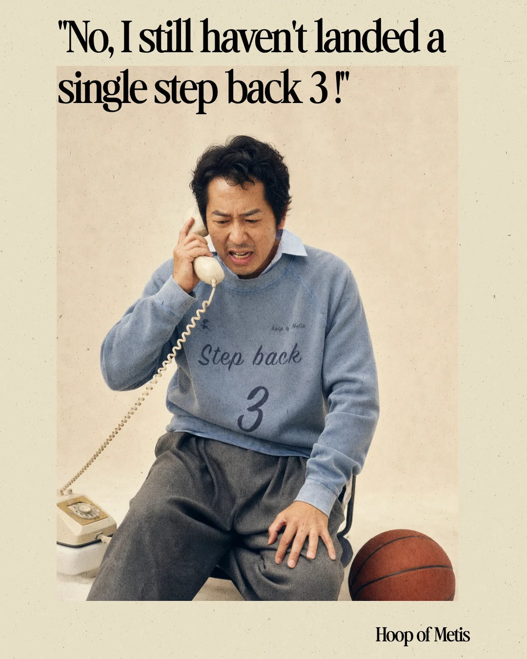 A vintage-style promotional photo of a man sitting and talking on a rotary telephone, wearing a light blue sweatshirt with the words 'Step back 3' and dark sweatpants. A basketball is on the floor beside him.
